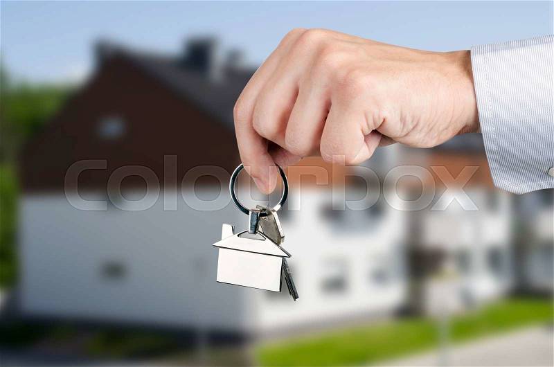 Man hand holding keys with to new house. Home shape chrome pendant , stock photo
