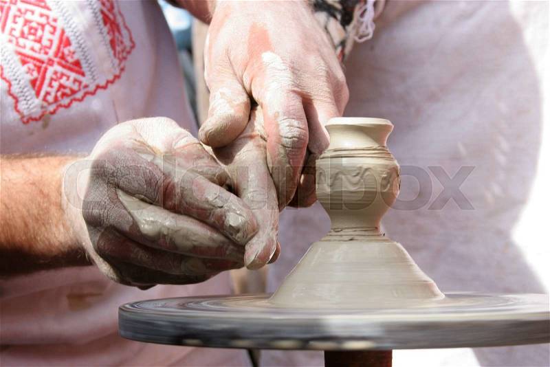 Hands of Ukrainian ceramic master and his disciple during clay workshop. Closeup shot of hands making clay product, stock photo