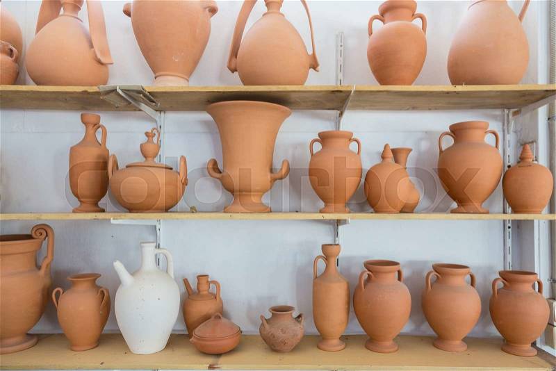 Shelves with different brown clay jars and pots made by greek artists, stock photo