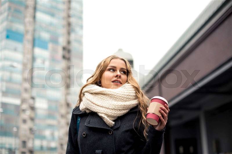 Pretty young blonde drinking coffee outside on a cloudy day, stock photo