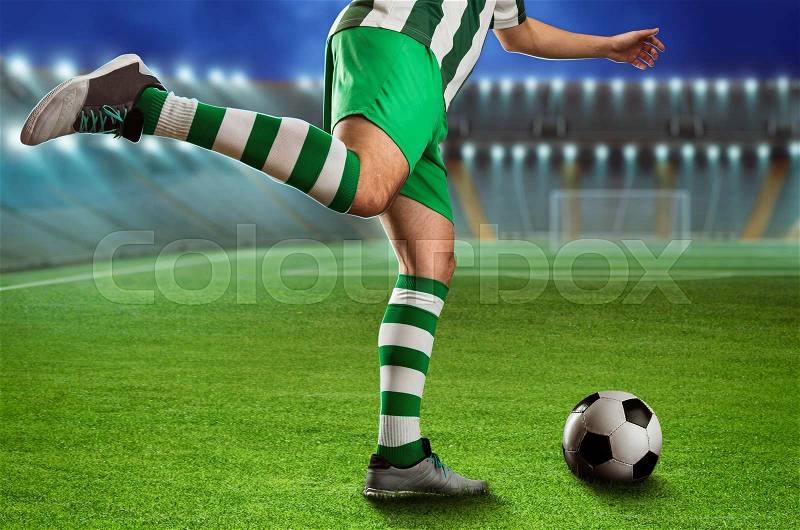Football-player kicking the ball on the football ground, stock photo