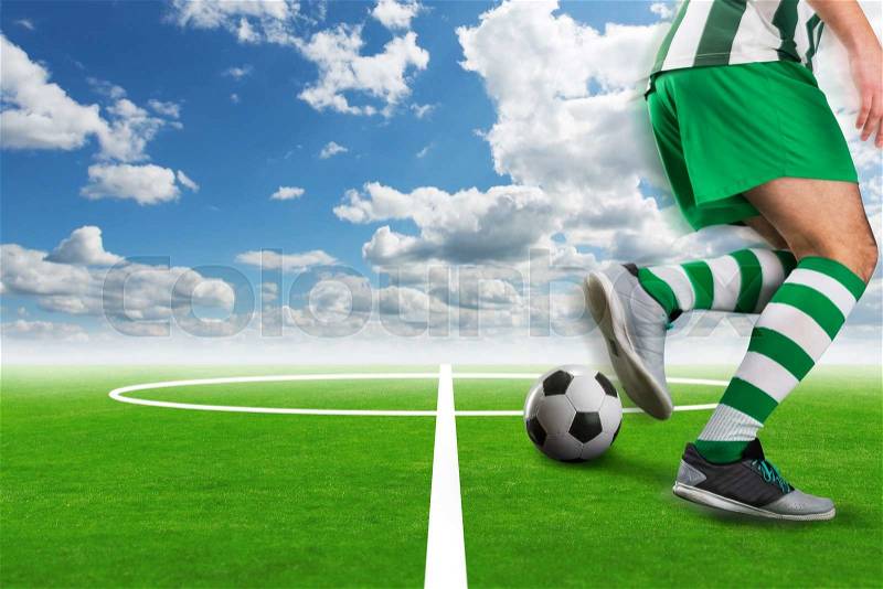 Football-player kicking the ball on the football ground outdoor, stock photo