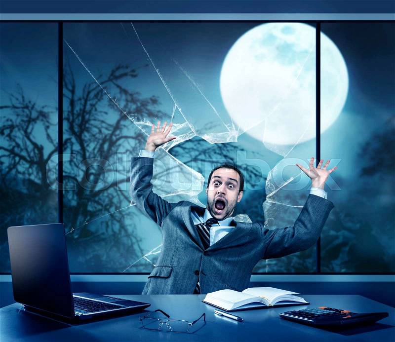 Scared businessman in the office, full moon outside, stock photo
