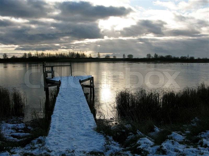 Fishing bridge on a frozen lake in winter, covered by snow, stock photo