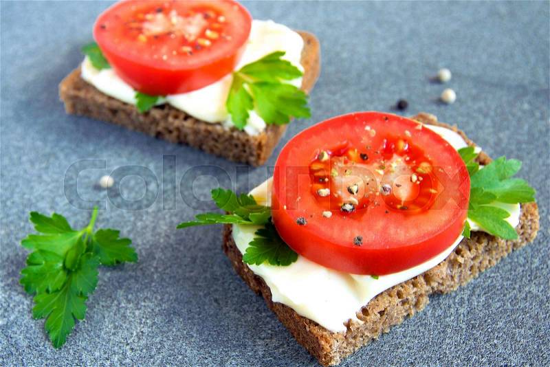 Vegetarian sandwiches with cream cheese, tomatoes, parsley and black pepper on grey background, stock photo