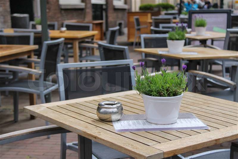 Pots with decorative flowers on the tables of outdoor street cafe, stock photo