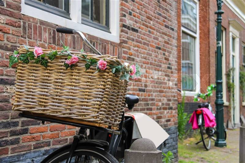 Bicycle with flower decorated wicker basket near the brick house, stock photo