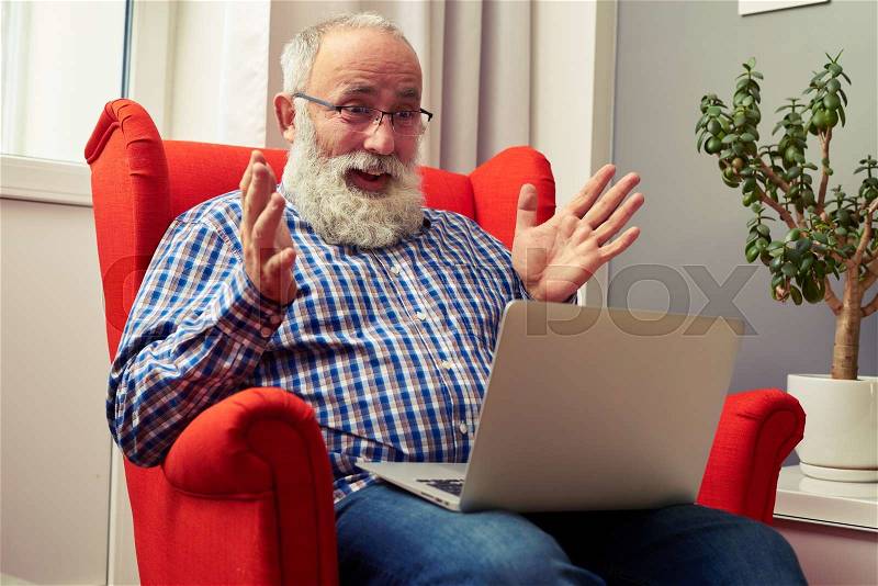 Amazed senior man sitting on the chair and looking at laptop , stock photo