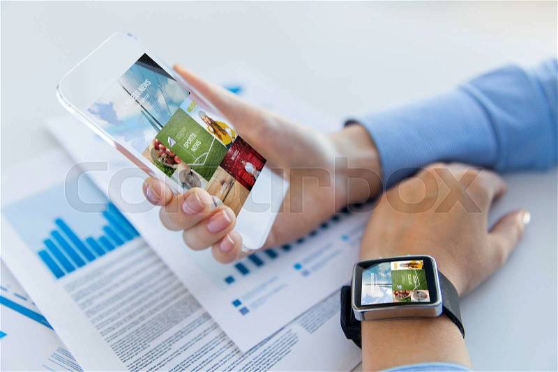 Business, technology, media and people concept - close up of woman hand holding transparent smartphone and wearing smartwatch with news application, stock photo