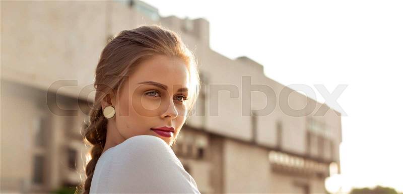 Woman resting on the street looks into the distance, stock photo