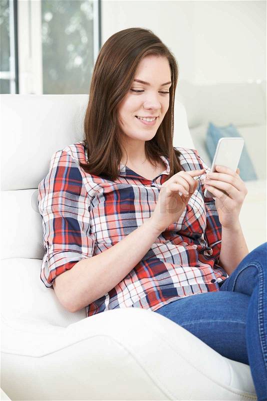 Teenage Girl Sending Text Message From Mobile Phone At Home, stock photo