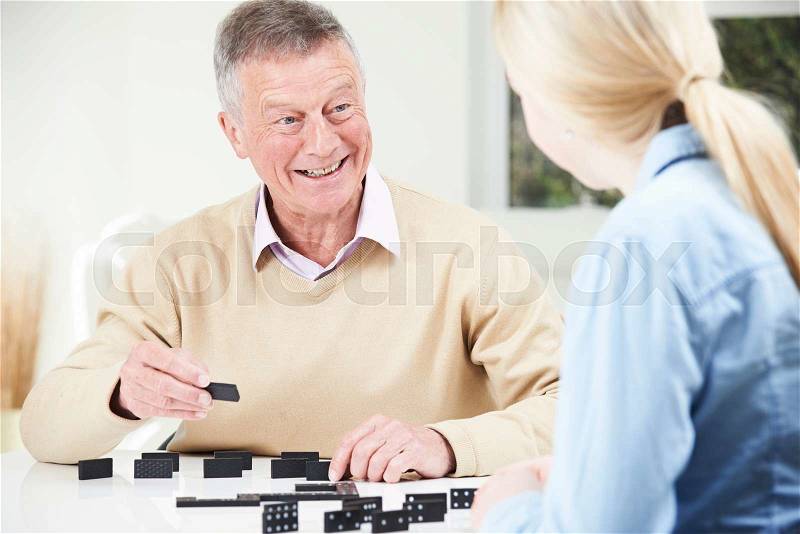 Senior Man Playing Dominoes With Teenage Granddaughter, stock photo