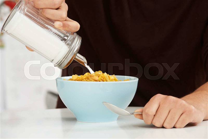 Young Man Adding Sugar To Breakfast Cereal, stock photo