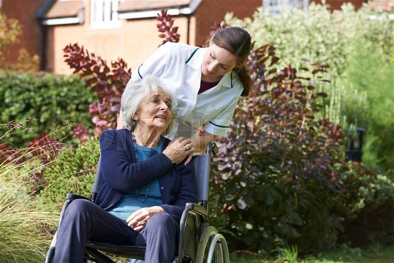 Carer Pushing Senior Woman In Wheelchair, stock photo