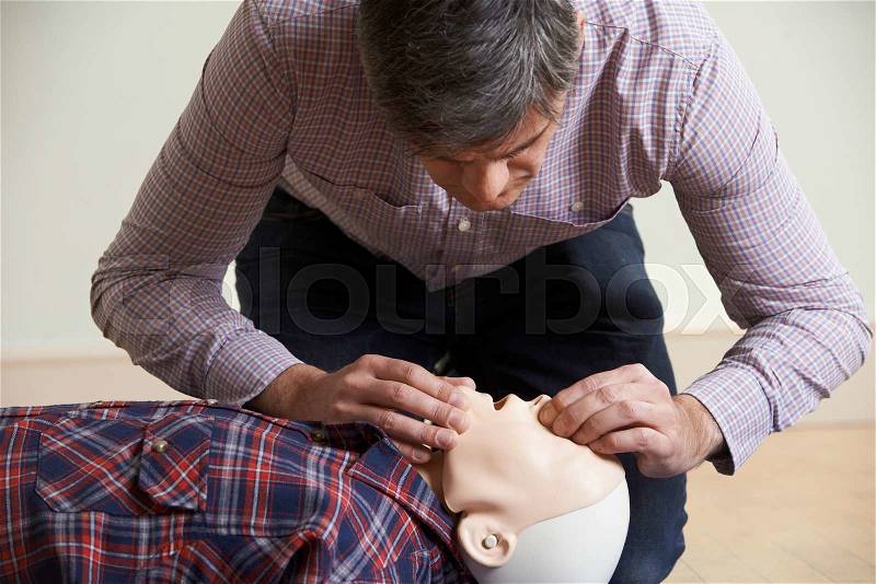 Man In First Aid Class Performing Mouth To Mouth Resuscitation On Dummy, stock photo