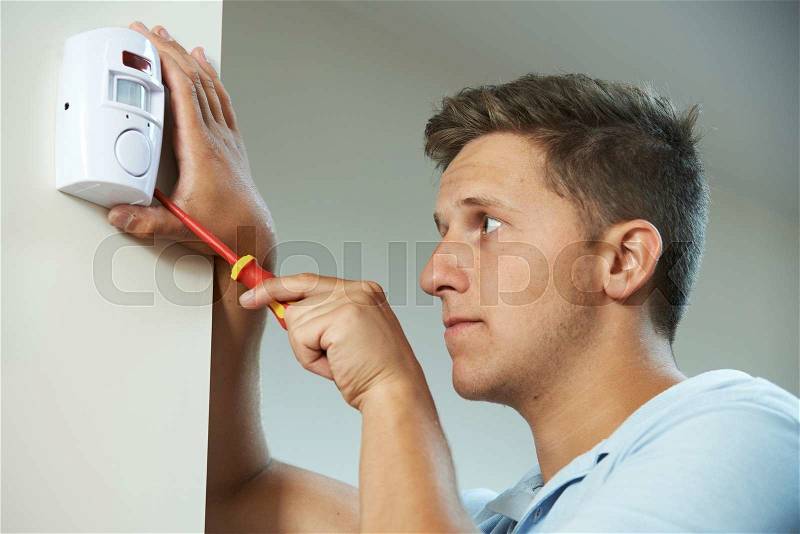 Security Consultant Fitting Burglar Alarm Sensor In Room, stock photo