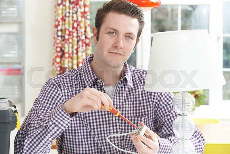 Man Wiring Electrical Plug On Lamp At Home, stock photo
