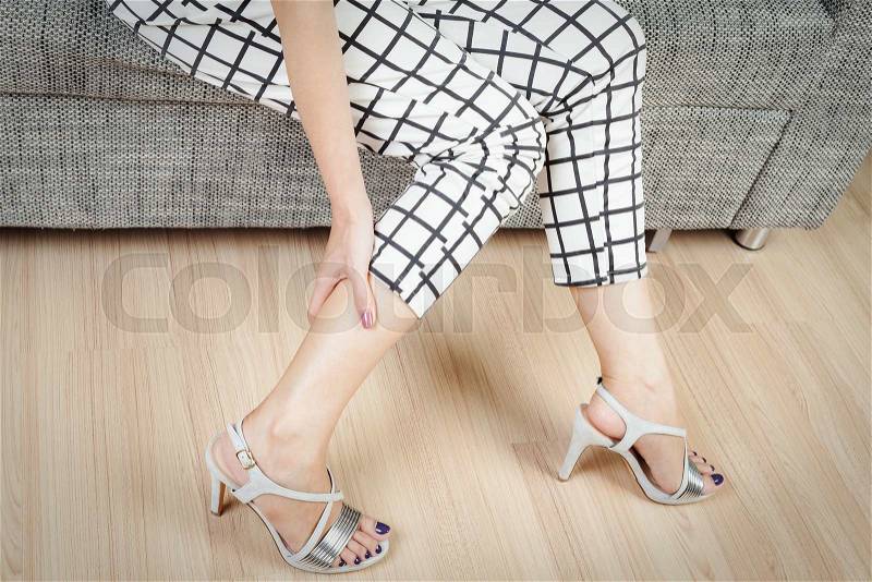 Woman sit on chair and female hand with foot pain after, take shoes off, stock photo