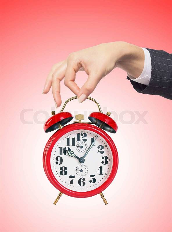 An alarm clock in woman hand over red background, stock photo