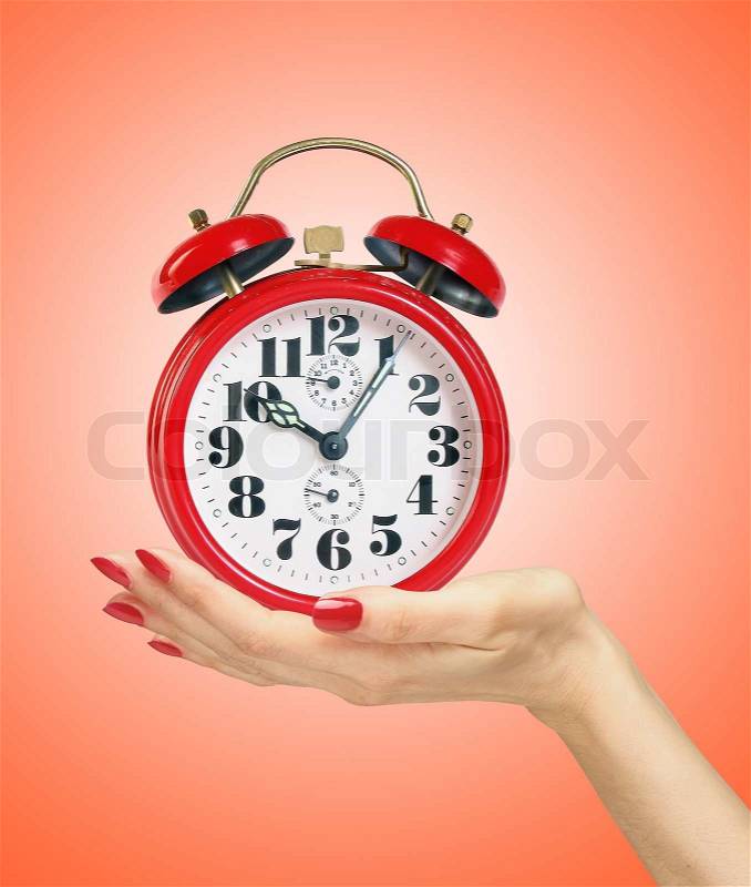 Red alarm clock in woman hand over red background, stock photo