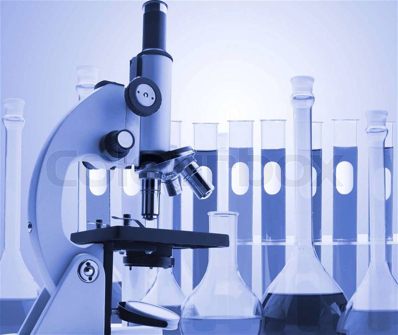 Laboratory metal microscope and test tubes with liquid toning in blue color, stock photo