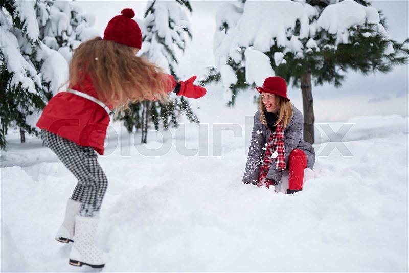 Daughter and mother playing with snow in park, stock photo