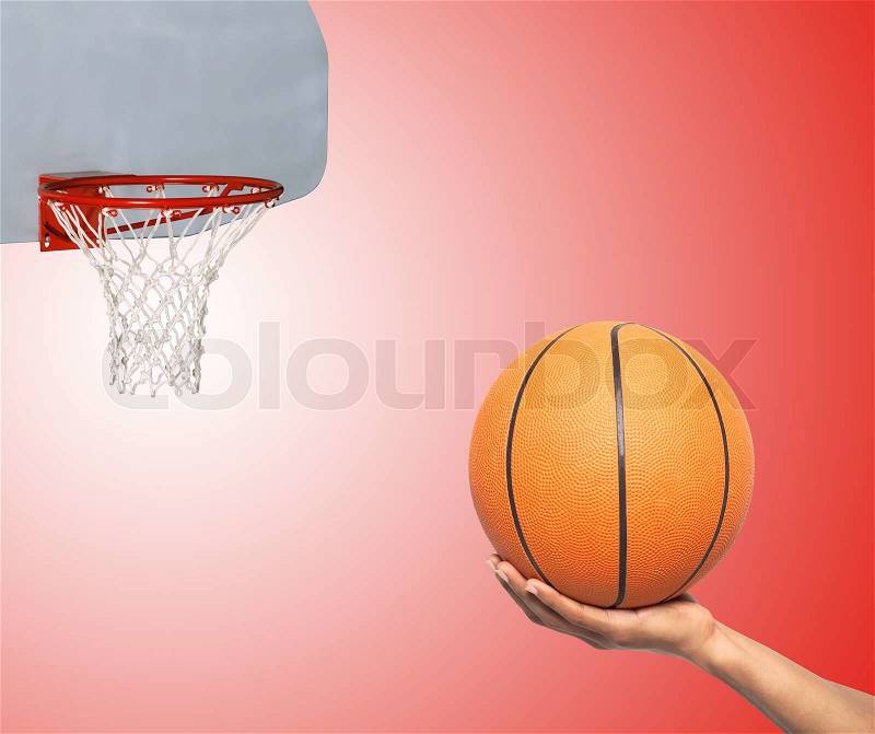 Basketball in hand and basket over red background, stock photo