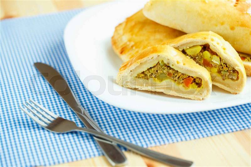 Delicious cake stuffed with meat on a white plate and blue checkered tablecloths, stock photo
