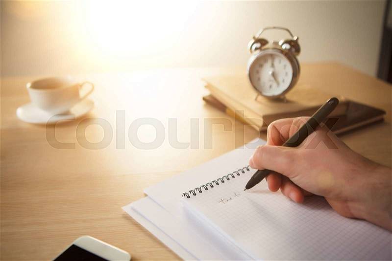 The male hand with a pen and the service hours and notebook on the table, stock photo