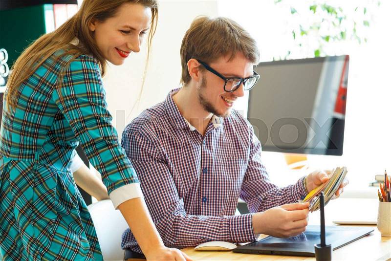 Young colleague - man and woman looking to a color paint palette at home office, modern business concept, stock photo
