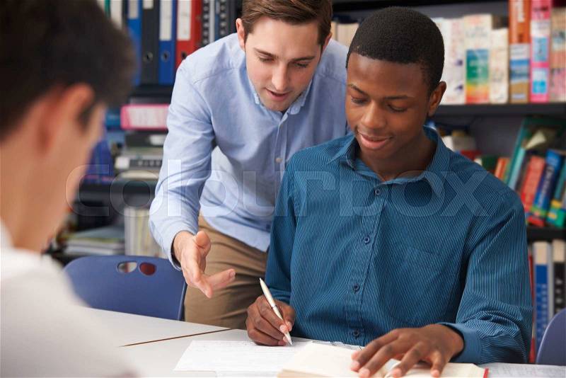 Teacher Helping Male Pupil In Class, stock photo