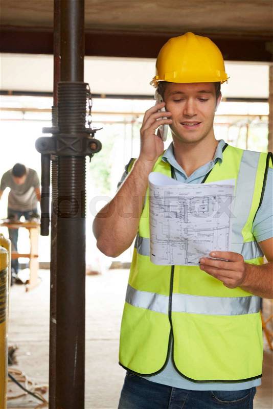 Builder On Site Using Mobile Phone, stock photo