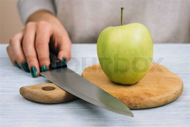 Woman going to cut green apple with a kitchen knife, stock photo