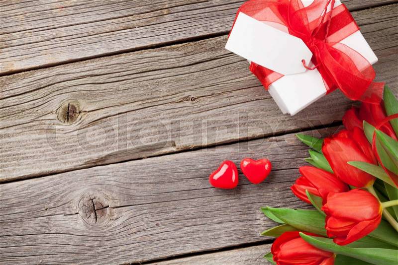 Red tulips, gift box and Valentine\'s day candy hearts on wooden table. Top view with copy space, stock photo