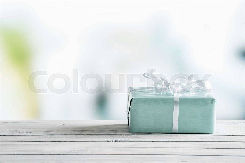 Blue gift box on a wooden table in bright light, stock photo