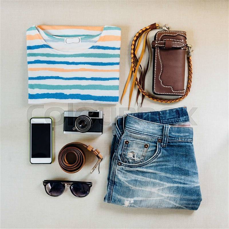 Travel accessories. Sweaters, jeans, cellphone, belts, wallets, glasses and camera ready for a trip, stock photo