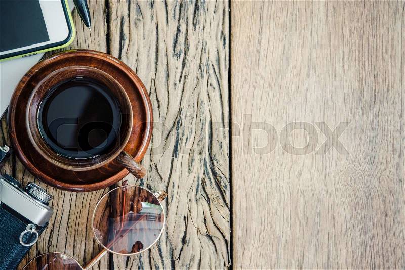 Ready to travel, coffee cup,camera, glass and phone on old wood table with free copy space. Vintage filtered, stock photo