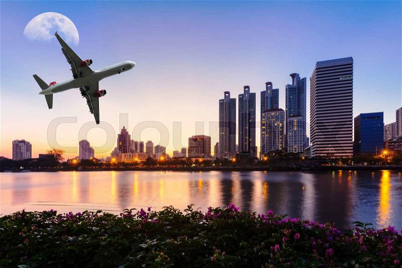 Modern building with flower, airplane and moon in the sky at twilight in Bangkok, Thailand, stock photo
