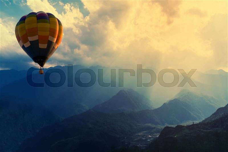 Colorful hot-air balloons flying over the mountain with sunbeam or ray, stock photo