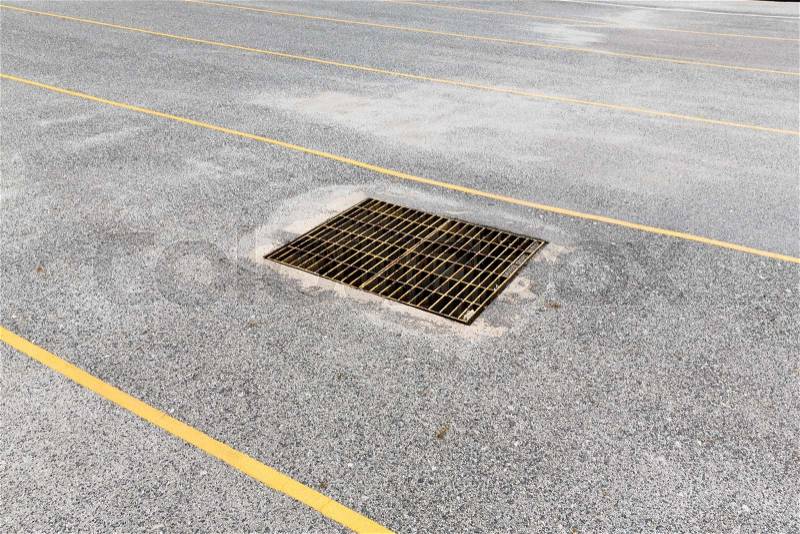 Concrete road with steel sewer drain grid, stock photo