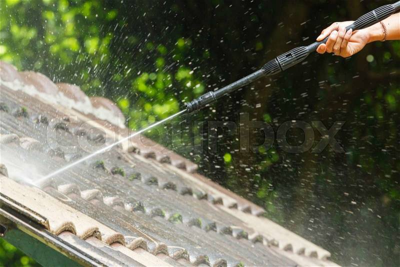Roof cleaning with high pressure water cleaner, stock photo