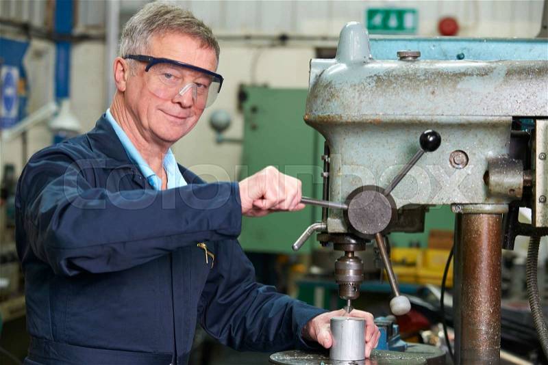 Skilled Engineer Using Drill In Factory, stock photo