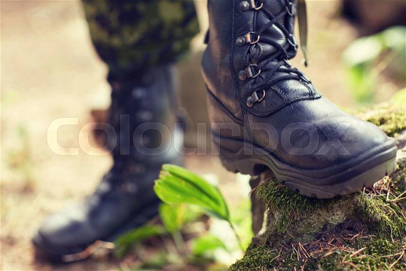 War, hiking, army and people concept - close up of soldier feet in army boots in forest, stock photo