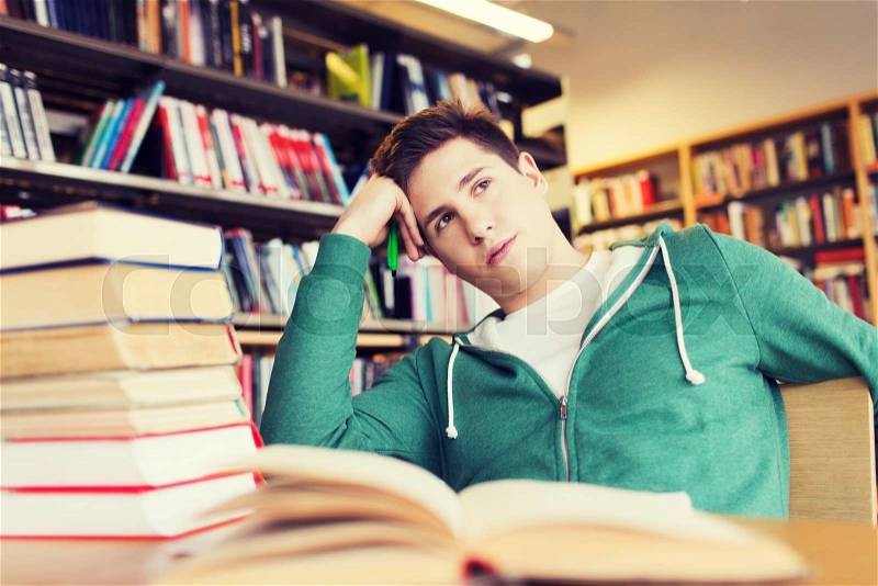 People, knowledge, education, literature and school concept - bored student or young man with books dreaming in library, stock photo