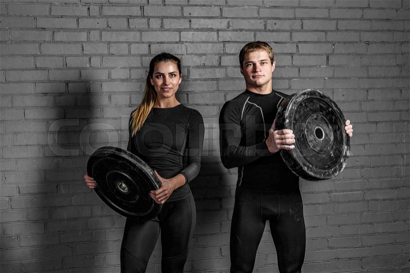 Couple of sporty man and woman holding barbells in hands and smiling. love sports, stock photo