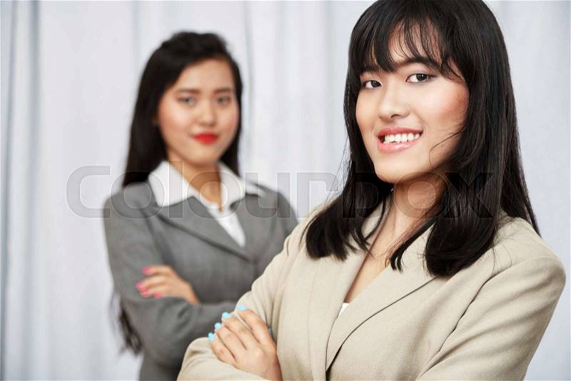 Close up of businesswomen wearing suits standing and folding arms, stock photo