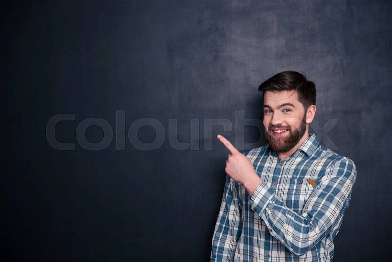 Happy man pointing finger away over black background, stock photo