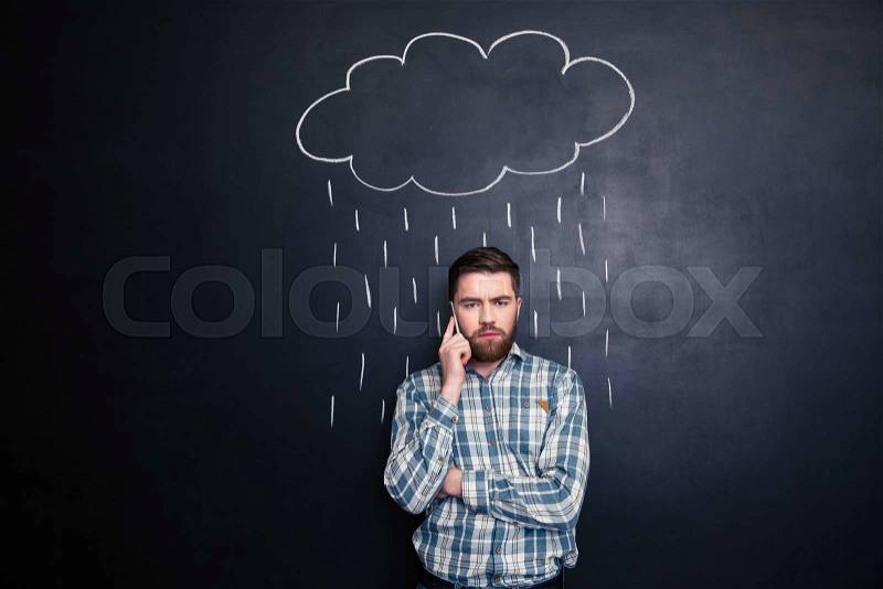 Man talking on mobile phone under rain drawn at blackboard, stock photo