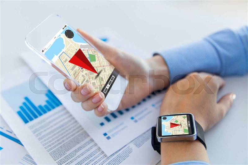Business, technology and people concept - close up of woman hand holding transparent smartphone and smart watch with navigator map on screen at office, stock photo