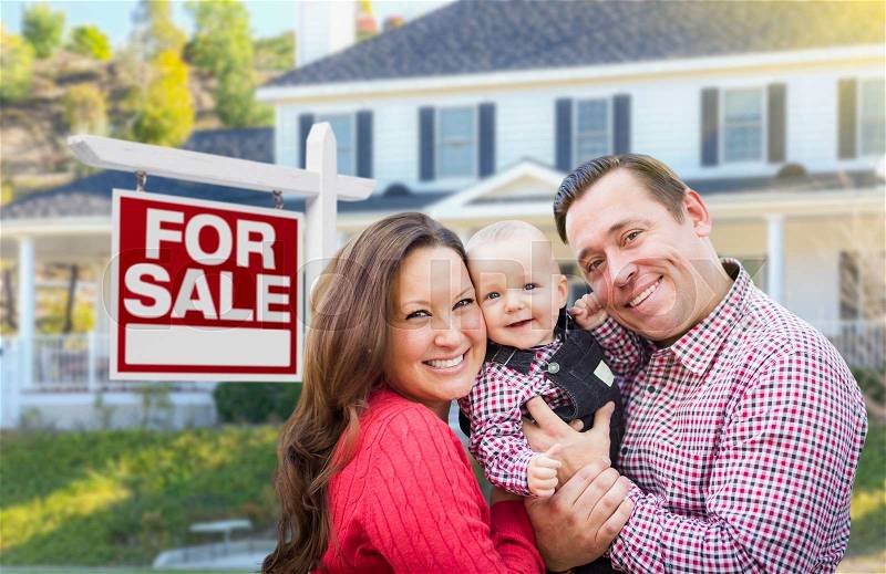 Happy Young Family In Front of For Sale Real Estate Sign and House, stock photo